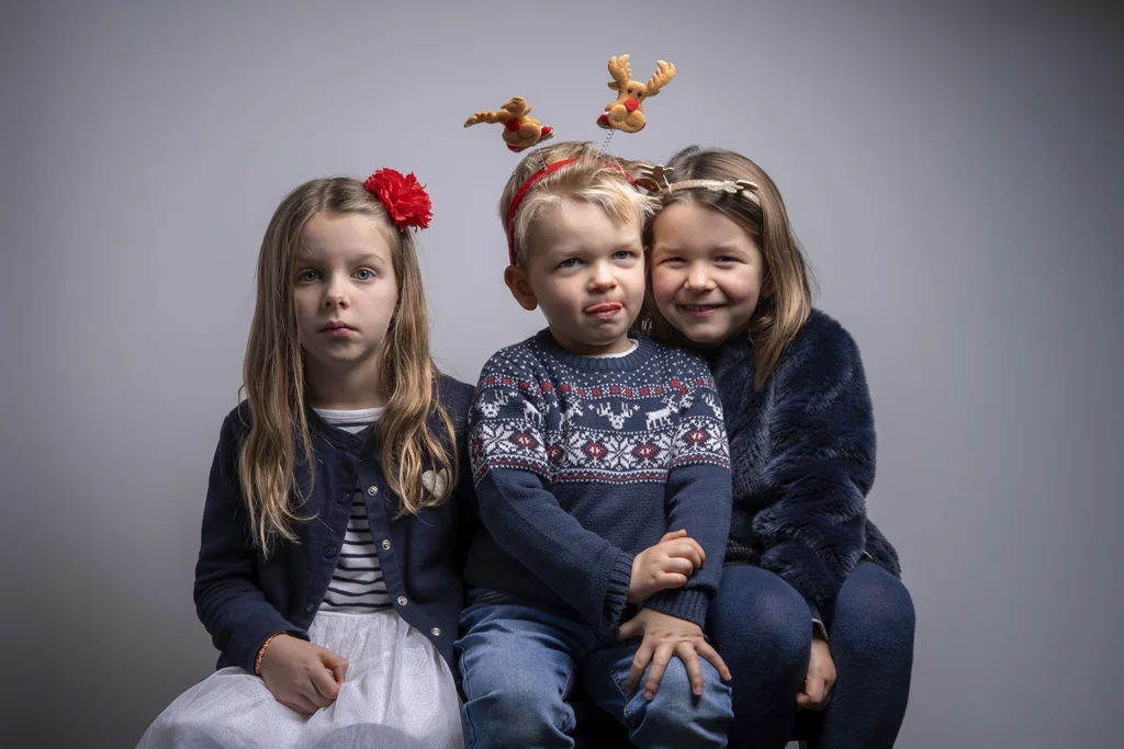 Portrait d'un frère avec ses deux sœurs lors d'une séance photo de Noël.