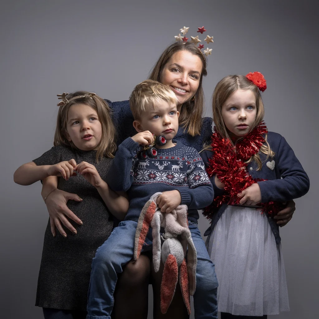 Portrait d'une maman réunie avec ses trois enfants dans un décor de Noël.