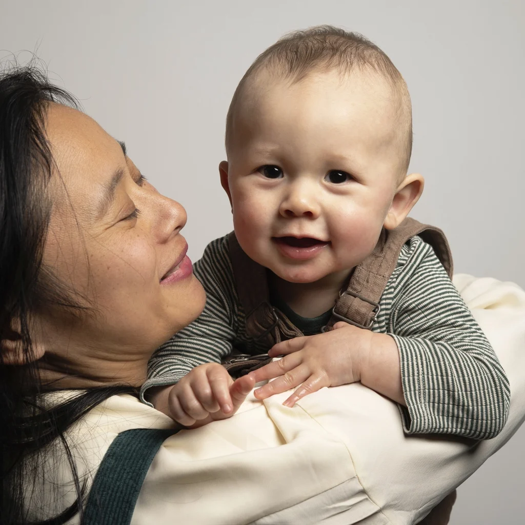 Une mère regarde tendrement son bébé dans ses bras.