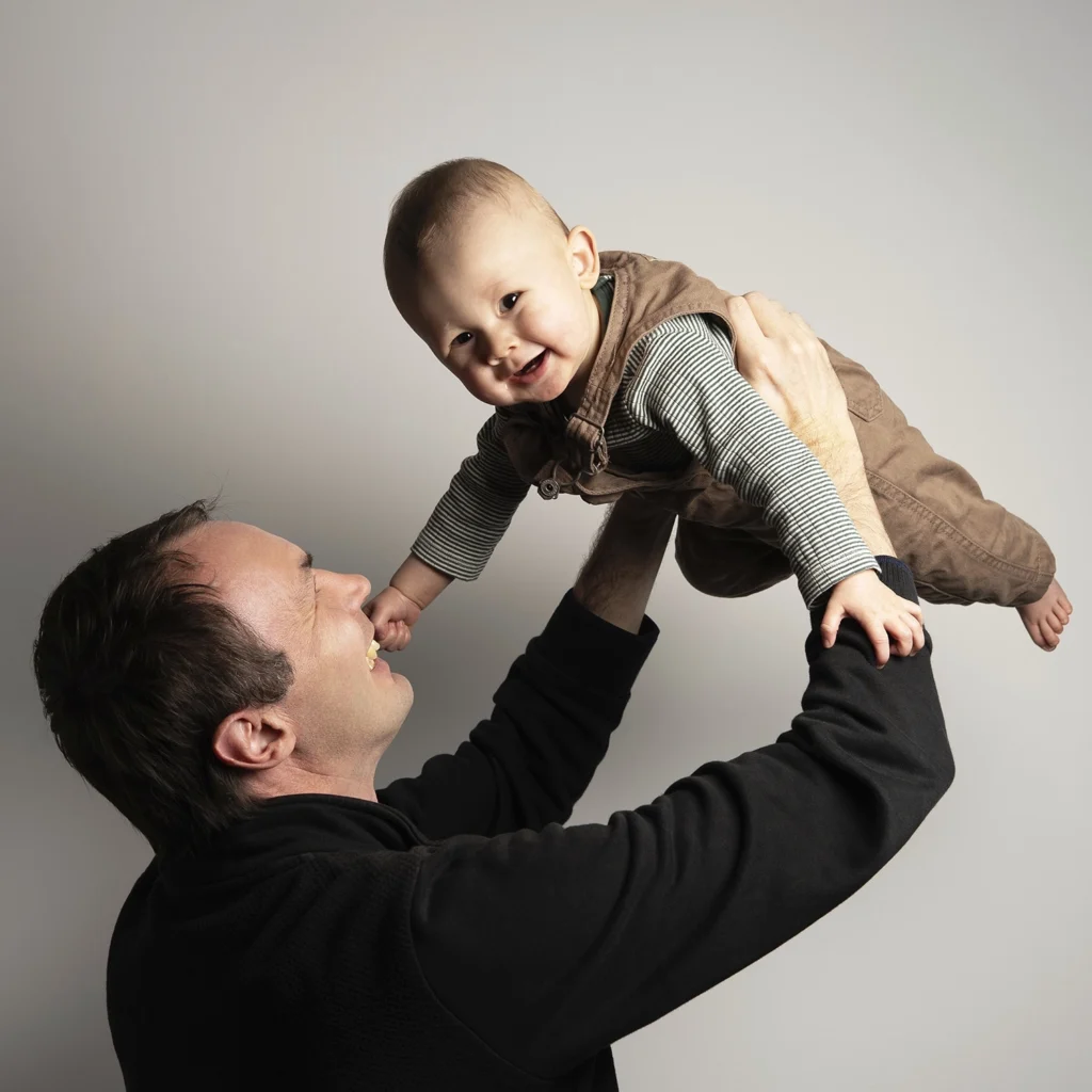 Portrait d'un père avec son bébé dans les bras.